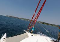 crew removing gennaker from bow of sailing trimaran yacht